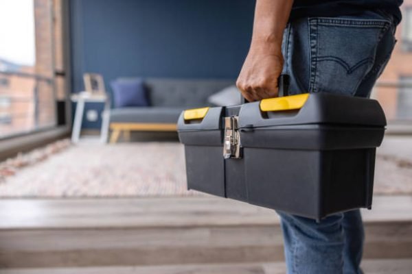 Close-up on an electrician carrying a toolbox while working at a house - domestic life concepts