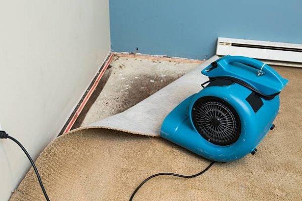 Water damaged walls and floors in house. Dehumidifier pointing at walls.