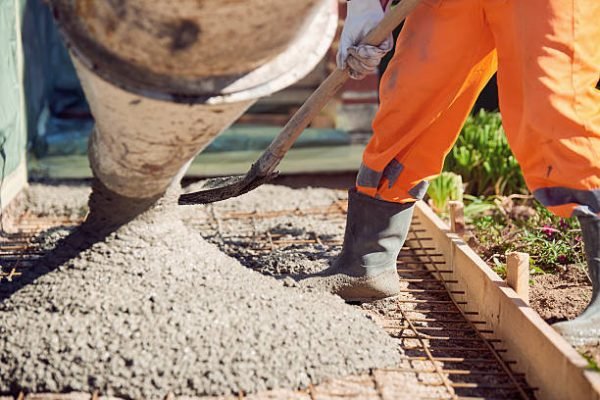 Worker with gum boots spreading ready mix concrete